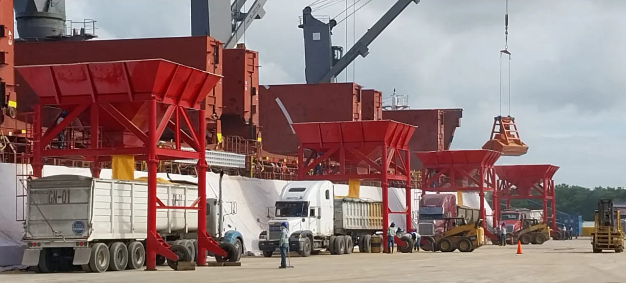 Tolvas y unidades de transporte en operación de descarga de graneles